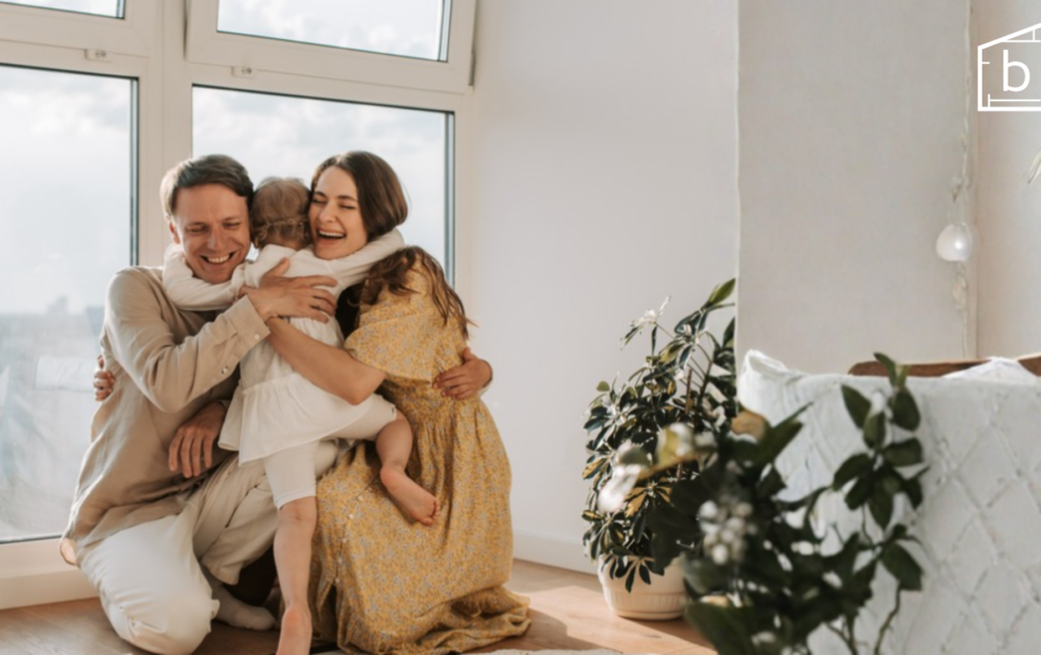 happy mom, dad, and child hugging in their home