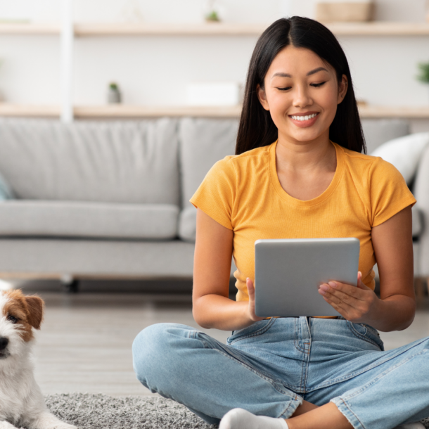 woman sitting on floor with ipad and small brown and white dog next to her