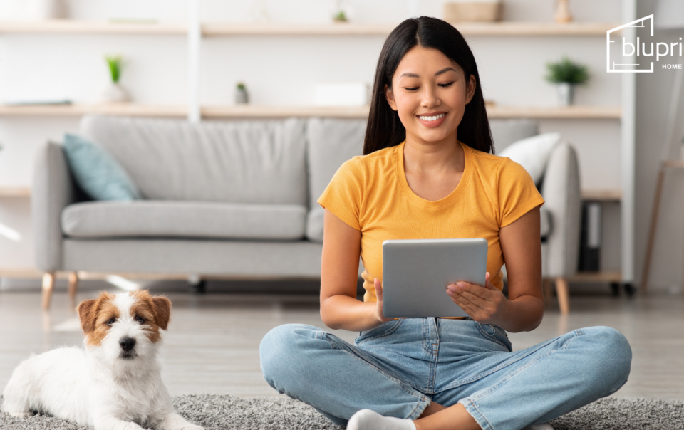 woman sitting on floor with ipad and small brown and white dog next to her
